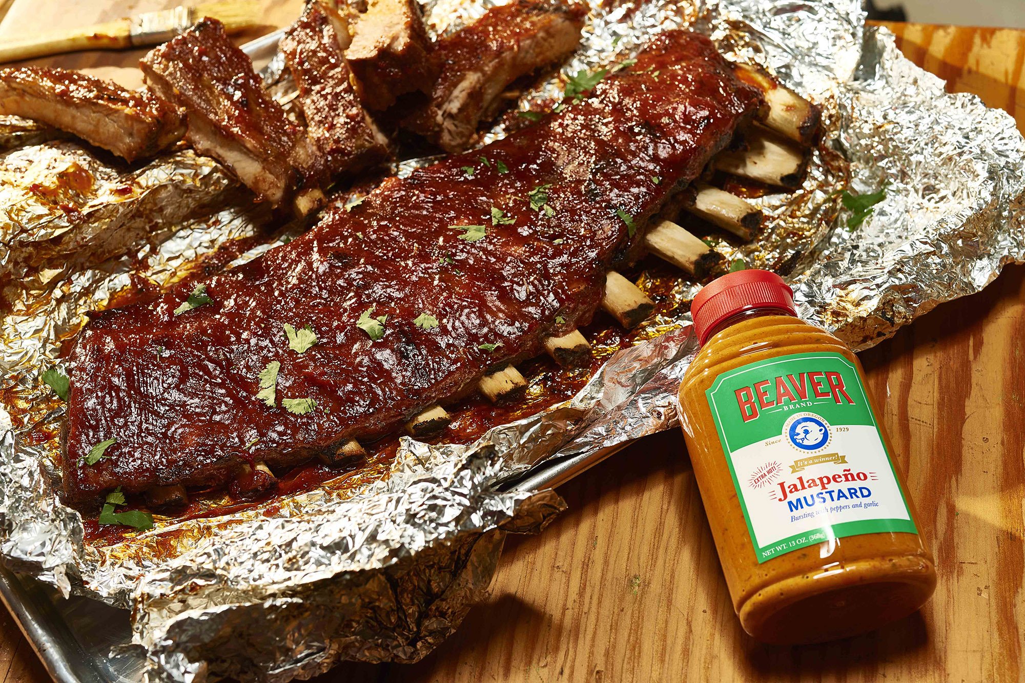 beaver-brand-jalapeno-ribs_slider Rack of ribs on foil with Beaver Brand Jalapeño Mustard